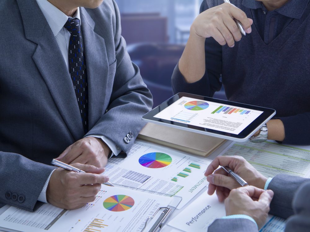 Businessmen are deeply reviewing financial reports for a return on investment or investment risk analysis and business performance.